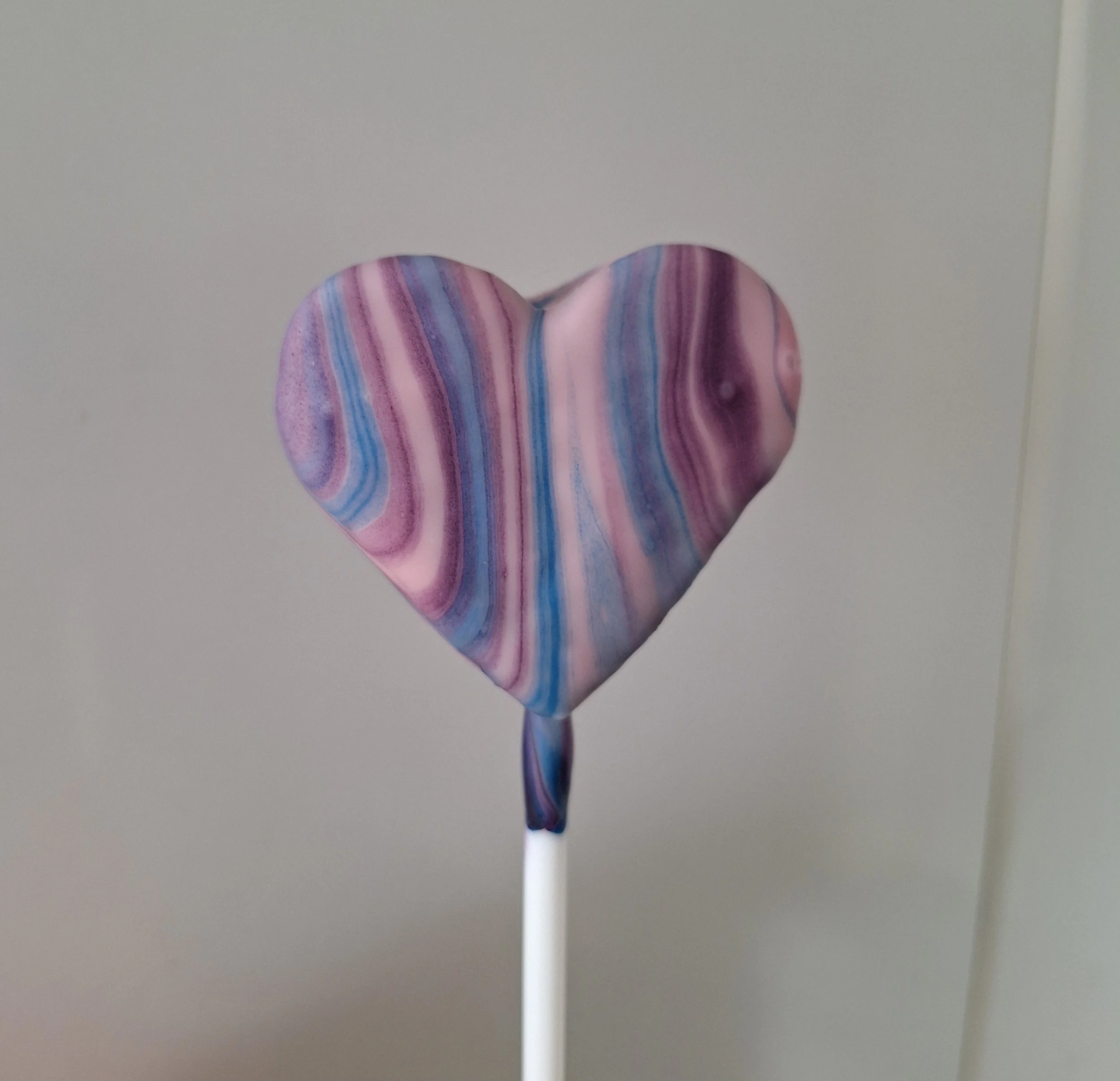 Heart-shaped cake pop with pink, purple and blue marbled coating