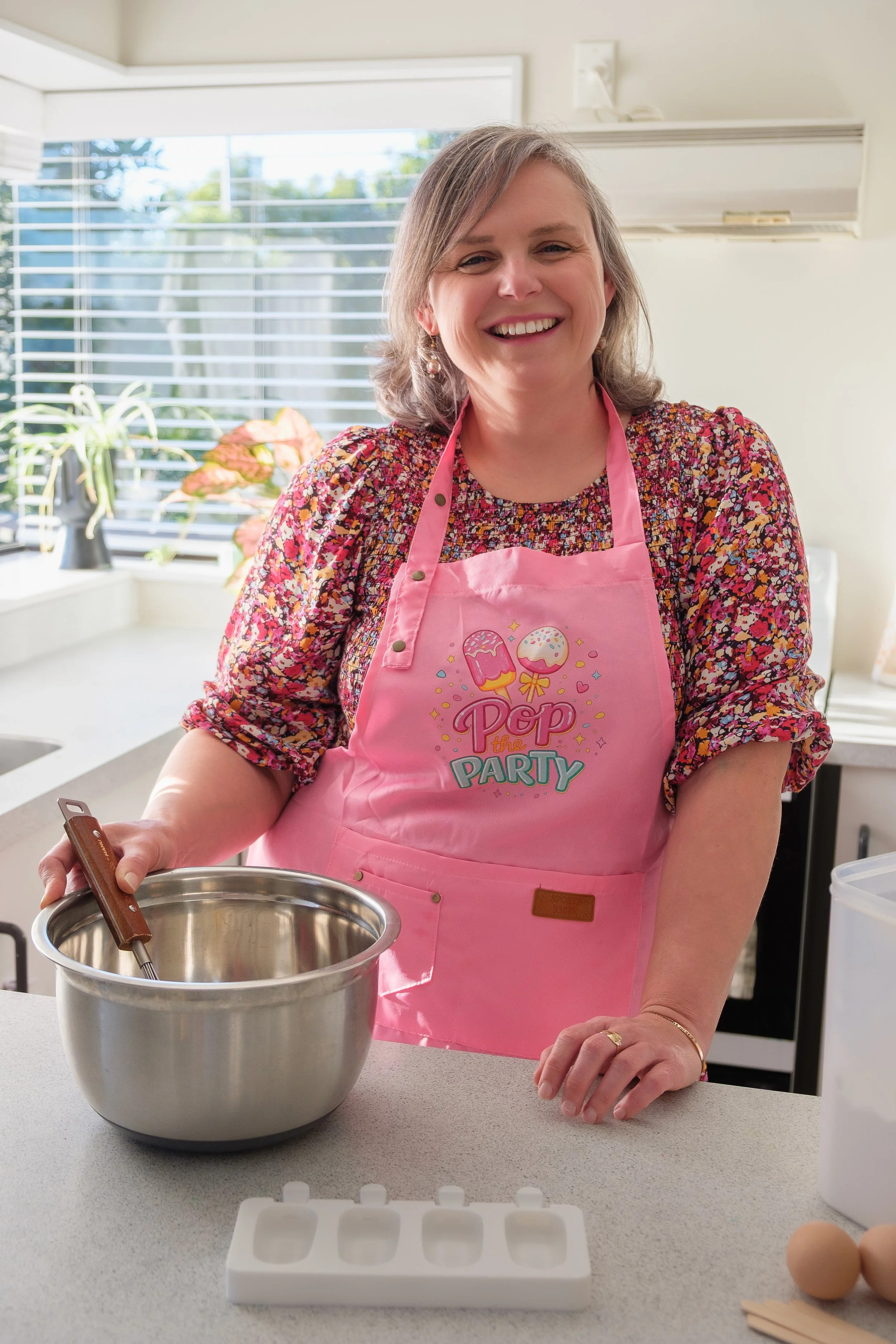 Eve wearing a pink apron beside a mixing bowl in her kitchen